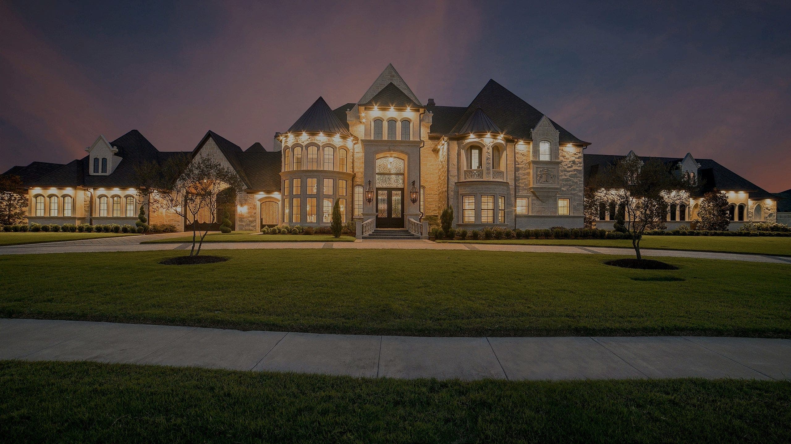 A grand custom stone estate glowing at dusk
